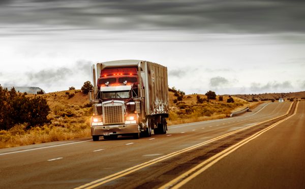 A semi-truck on the highway at dusk